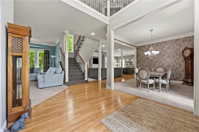 14692 S Garnett St, Olathe, KS 66062 - dining room featuring wallpapered walls, a chandelier, stairs, crown molding, and an accent wall