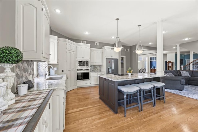 14692 S Garnett St, Olathe, KS 66062 - kitchen featuring stainless steel appliances, light wood-style flooring, a breakfast bar area, white cabinets, and recessed lighting