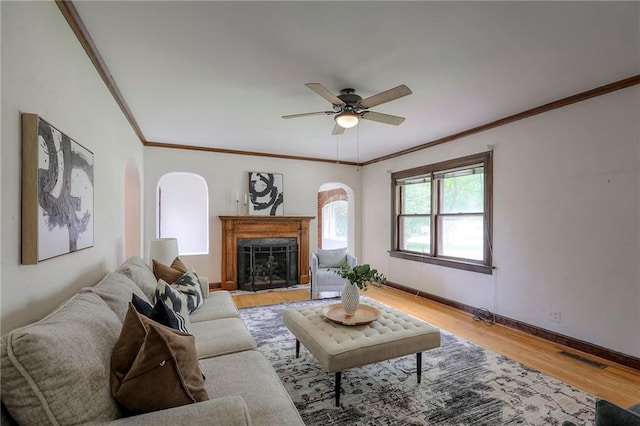 722 E Meyer Blvd, Kansas City, MO 64131 - living area featuring light wood-style floors, ornamental molding, a ceiling fan, a fireplace, and arched walkways