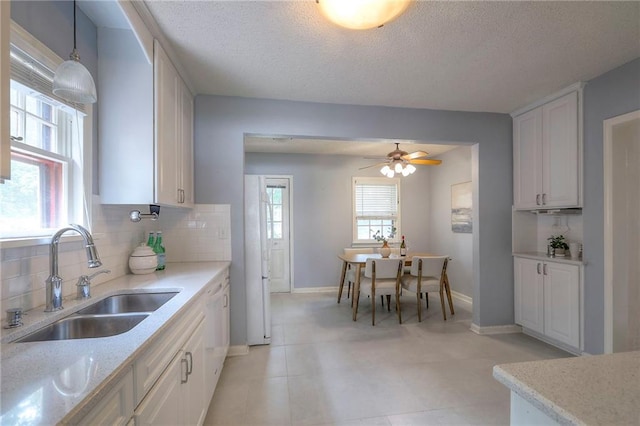 722 E Meyer Blvd, Kansas City, MO 64131 - kitchen with decorative backsplash, a textured ceiling, a ceiling fan, light stone countertops, and white cabinets