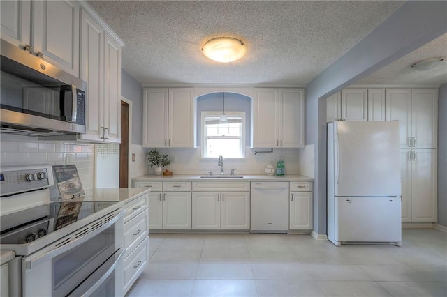 722 E Meyer Blvd, Kansas City, MO 64131 - kitchen featuring white appliances, a textured ceiling, light countertops, tasteful backsplash, and white cabinets