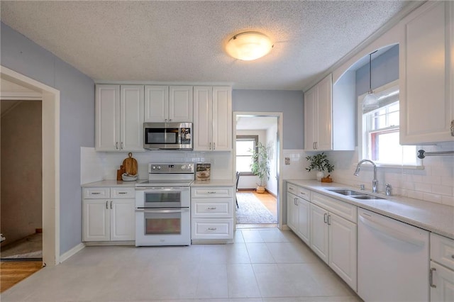 722 E Meyer Blvd, Kansas City, MO 64131 - kitchen featuring white appliances, healthy amount of natural light, decorative backsplash, light countertops, and a textured ceiling