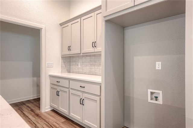 laundry room with baseboards, hookup for a washing machine, light wood-type flooring, and cabinet space