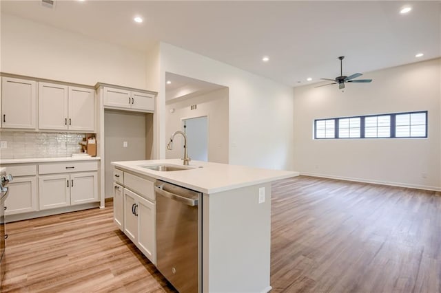 kitchen with a sink, light wood-type flooring, dishwasher, backsplash, and a ceiling fan