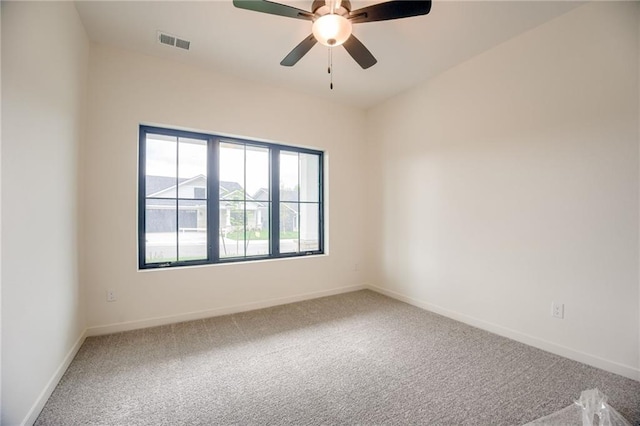 carpeted spare room featuring ceiling fan, baseboards, and visible vents