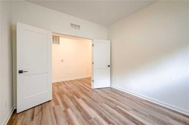 spare room featuring baseboards, light wood-type flooring, and visible vents