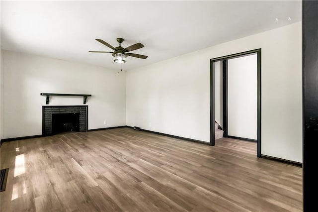 1910 Ottawa St, Leavenworth, KS 66048 - unfurnished living room featuring ceiling fan, wood finished floors, baseboards, and a brick fireplace