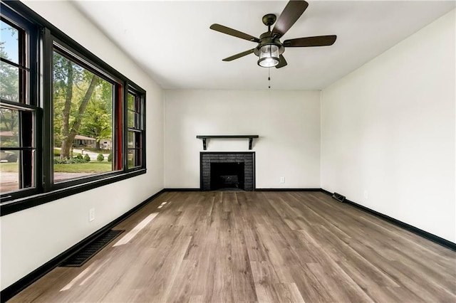 1910 Ottawa St, Leavenworth, KS 66048 - unfurnished living room featuring wood finished floors, a brick fireplace, ceiling fan, and baseboards