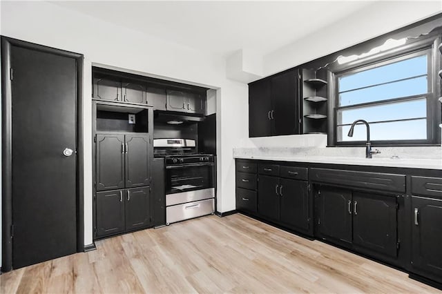 1910 Ottawa St, Leavenworth, KS 66048 - kitchen with stainless steel gas range, dark cabinetry, light countertops, light wood-style flooring, and open shelves