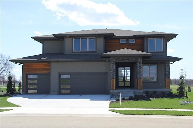 prairie-style home featuring an attached garage, a front lawn, and driveway