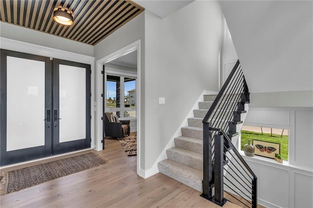 foyer entrance featuring baseboards, stairway, french doors, and light wood-style flooring