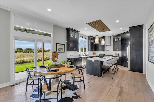 kitchen with visible vents, wall chimney exhaust hood, light countertops, dark cabinets, and a kitchen island