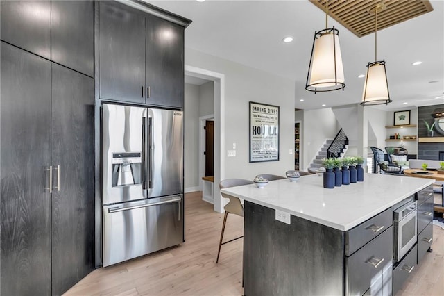 kitchen with stainless steel fridge with ice dispenser, light wood-type flooring, a center island, and decorative light fixtures