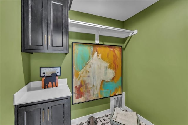 laundry room featuring hookup for an electric dryer, cabinet space, and baseboards