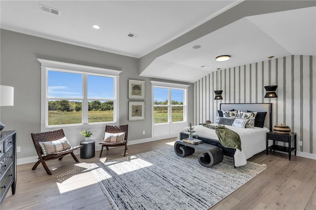 bedroom featuring baseboards, visible vents, wallpapered walls, and wood finished floors