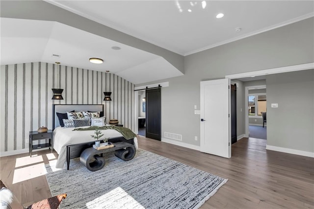 bedroom featuring baseboards, wood finished floors, a barn door, and vaulted ceiling
