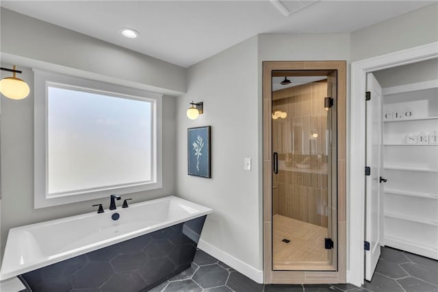 bathroom with a stall shower, tile patterned flooring, a freestanding bath, and a walk in closet