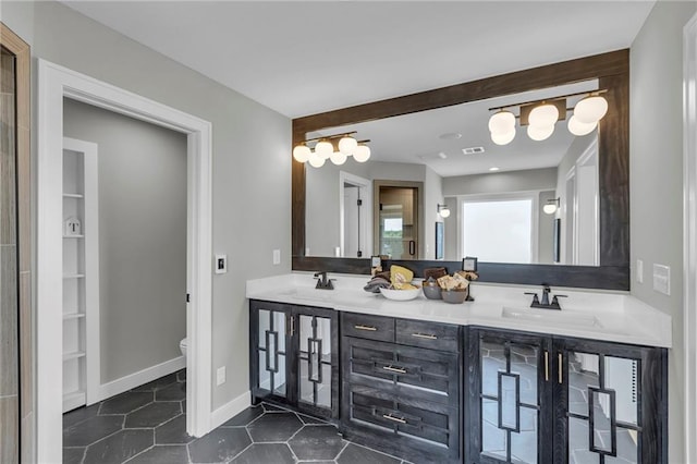 bathroom featuring toilet, tile patterned floors, double vanity, and a sink