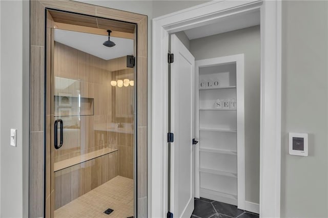 full bathroom featuring a stall shower, tile patterned flooring, and a spacious closet