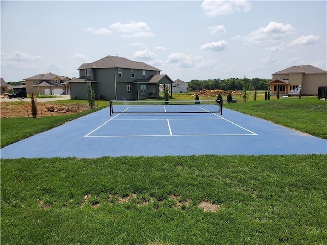 view of tennis court with a yard and fence