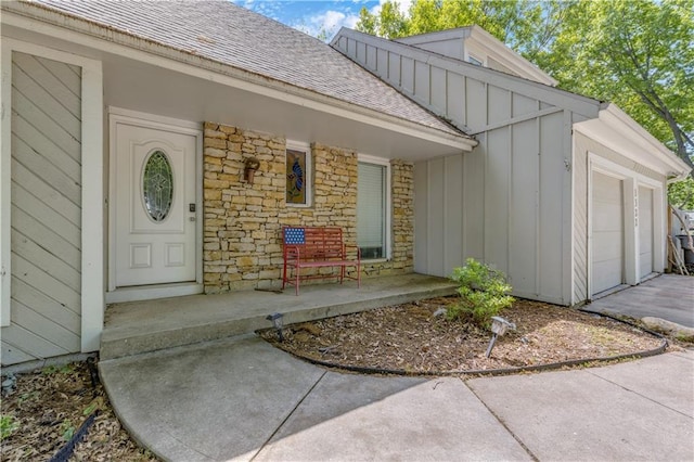 view of exterior entry with board and batten siding, a porch, roof with shingles, and driveway