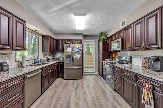 kitchen featuring a sink, appliances with stainless steel finishes, a textured ceiling, visible vents, and light wood-style floors