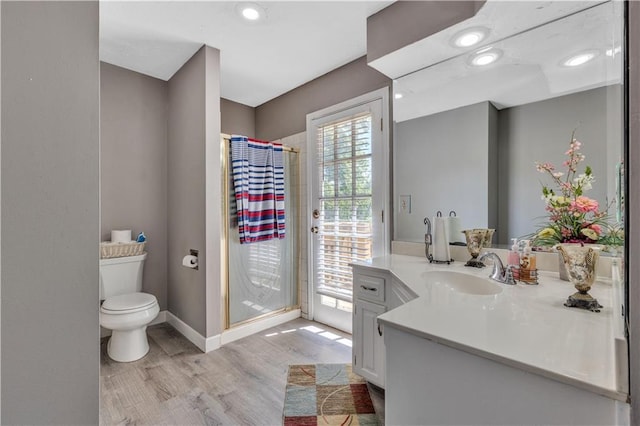 full bathroom featuring toilet, wood finished floors, vanity, a stall shower, and baseboards