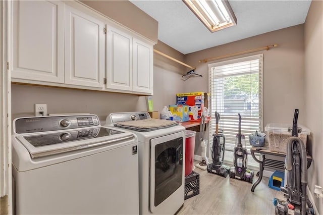 washroom with washing machine and clothes dryer, cabinet space, and wood finished floors