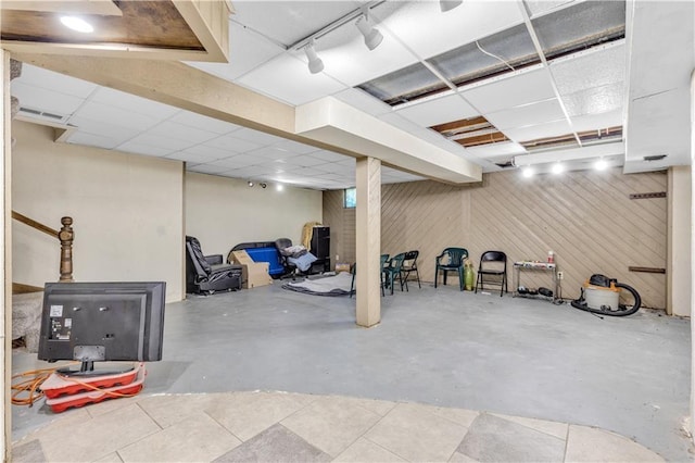 finished basement featuring rail lighting, visible vents, and a paneled ceiling
