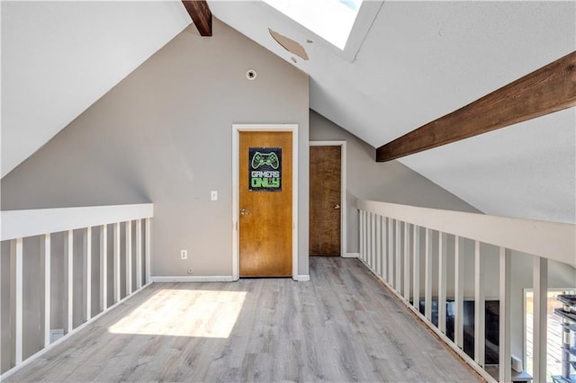 additional living space featuring vaulted ceiling with skylight and wood finished floors