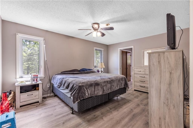 bedroom featuring a textured ceiling, light wood-style flooring, and ceiling fan