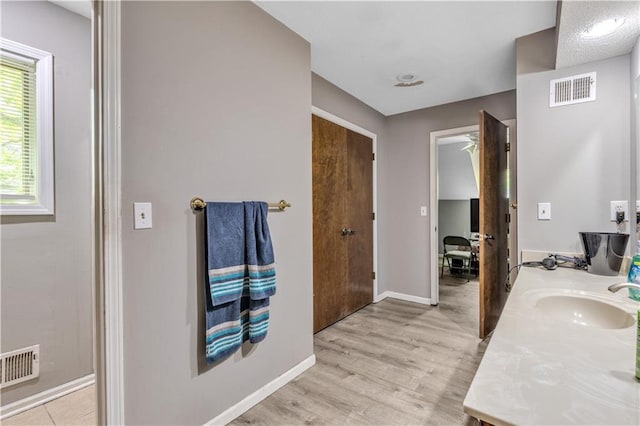 bathroom featuring a sink, baseboards, visible vents, and wood finished floors