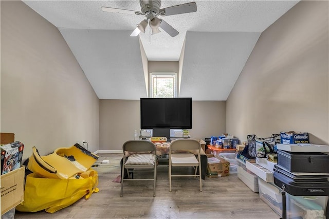 interior space featuring lofted ceiling, a textured ceiling, a ceiling fan, and wood finished floors