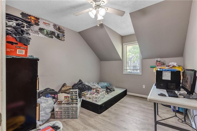 bedroom with wood finished floors, a ceiling fan, a textured ceiling, baseboards, and lofted ceiling