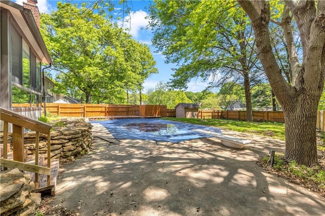 view of pool with a fenced backyard, a patio, a shed, and an outbuilding