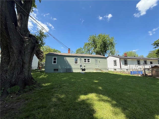 back of property featuring a yard, a chimney, and cooling unit