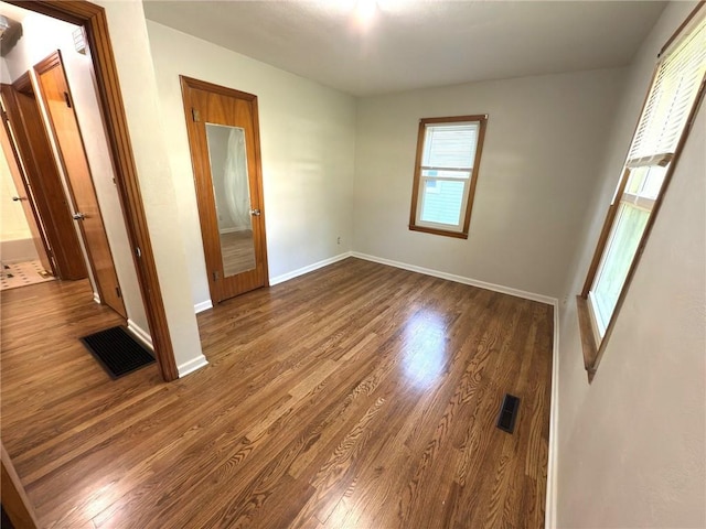 empty room with dark wood-style flooring and baseboards