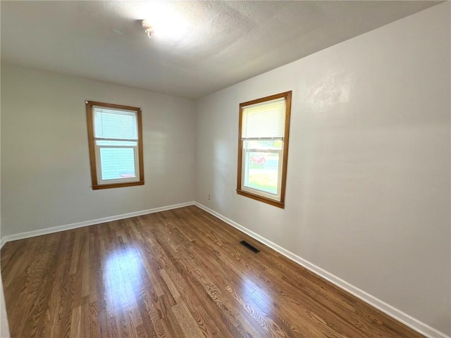 spare room with dark wood-style floors and baseboards
