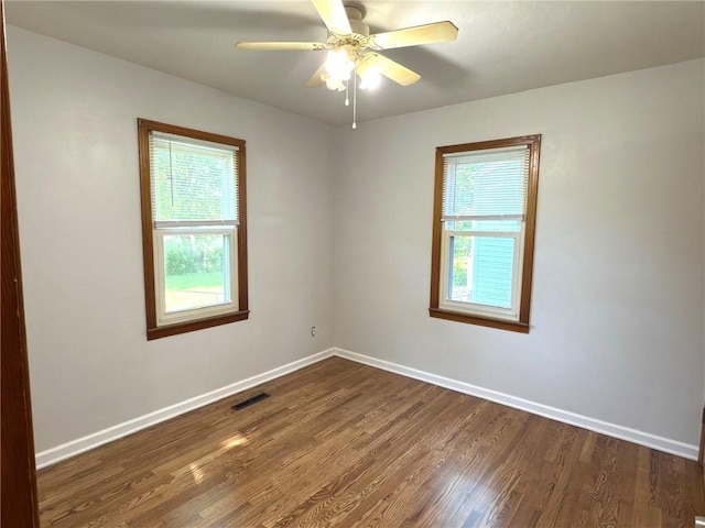 unfurnished room with plenty of natural light, dark wood-style flooring, baseboards, and ceiling fan