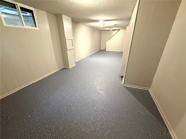 basement with a textured ceiling and baseboards