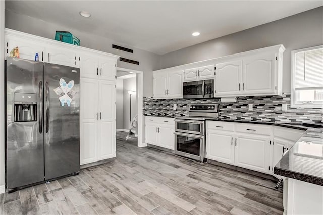 6700 N Charlston Dr, Kansas City, MO 64119 - kitchen with appliances with stainless steel finishes, dark countertops, white cabinets, tasteful backsplash, and recessed lighting