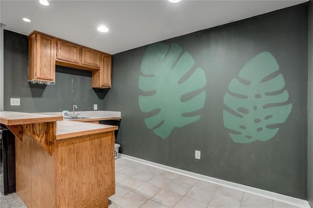 6700 N Charlston Dr, Kansas City, MO 64119 - kitchen with a peninsula, a sink, a breakfast bar area, light countertops, and brown cabinets