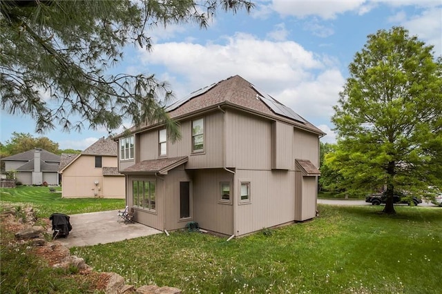 6700 N Charlston Dr, Kansas City, MO 64119 - back of house with a patio area, a yard, roof mounted solar panels, and roof with shingles