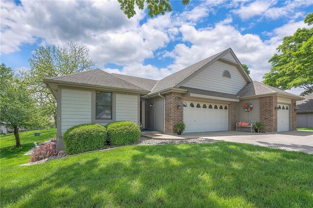 view of front of property with a garage, a front lawn, concrete driveway, brick siding, and roof with shingles