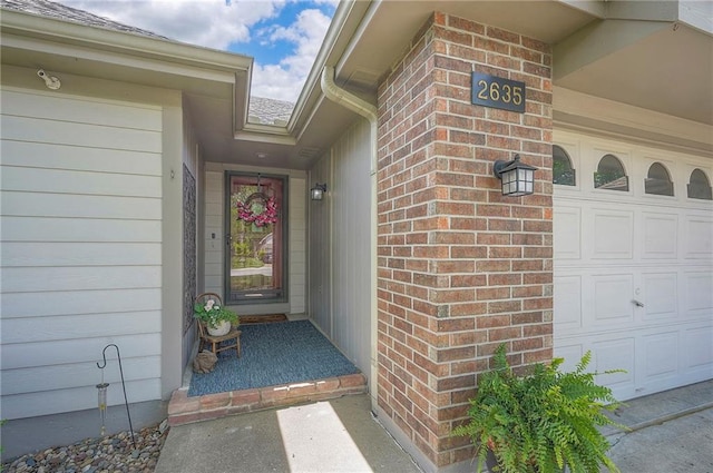 property entrance with a garage and brick siding