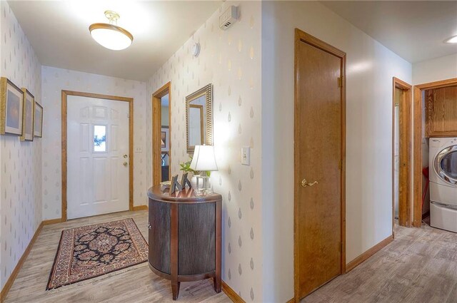 foyer entrance with wallpapered walls, light wood finished floors, baseboards, and washer / dryer