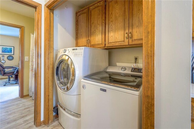 laundry room featuring cabinet space, washing machine and clothes dryer, and light wood-type flooring