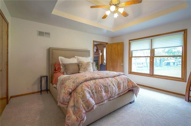 bedroom featuring carpet, baseboards, a tray ceiling, and a ceiling fan