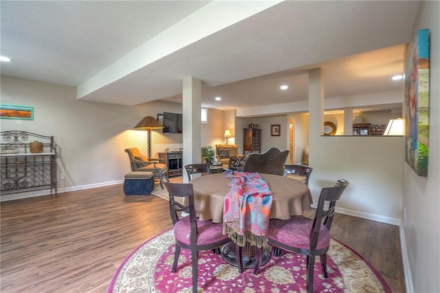 dining area featuring wood finished floors, baseboards, recessed lighting, a textured ceiling, and a fireplace
