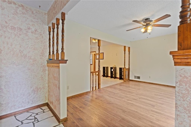 515 London Way, Belton, MO 64012 - unfurnished living room with wood finished floors, ceiling fan, baseboards, and a textured ceiling